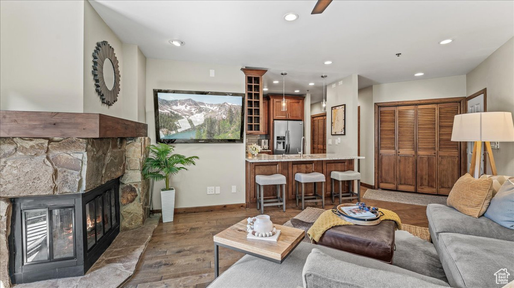 Living room featuring wood finished floors, recessed lighting, a stone fireplace, and baseboards