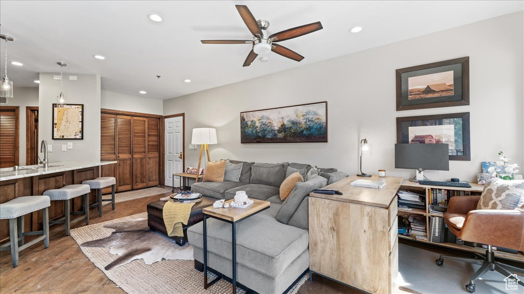 Living room with recessed lighting, a ceiling fan, and light wood-style floors