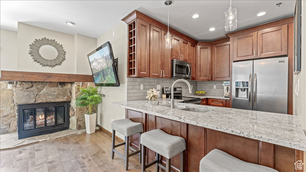 Kitchen featuring stainless steel appliances, a sink, light stone counters, light wood-style flooring, and recessed lighting