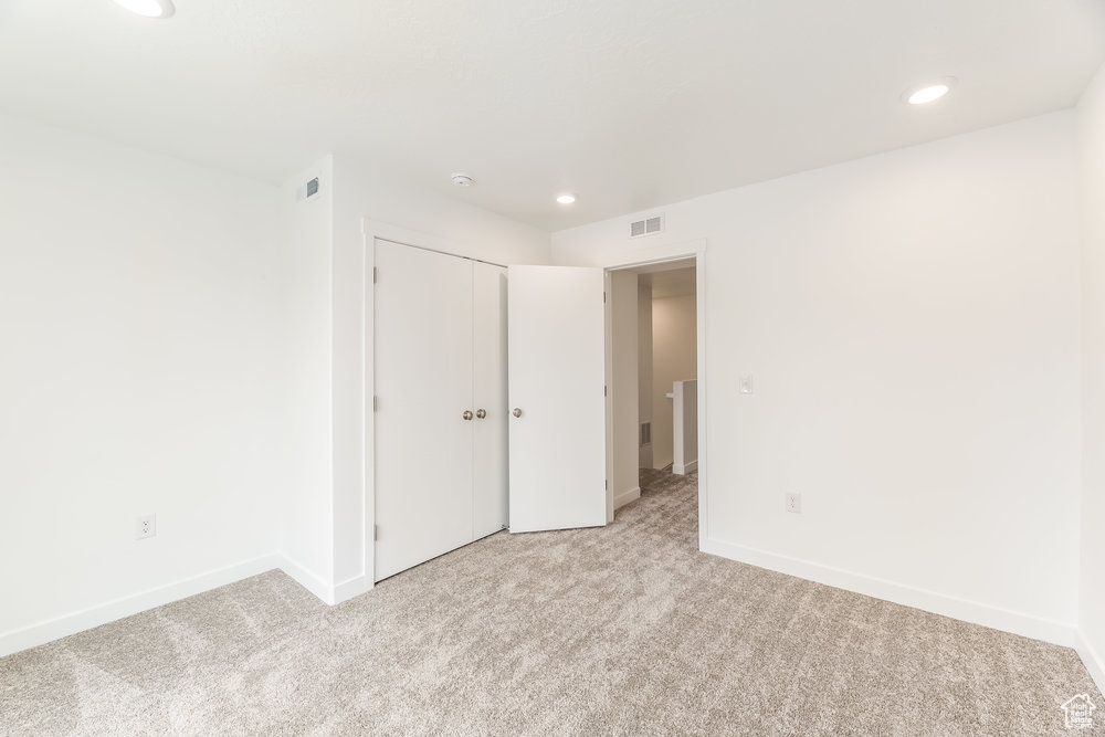 Unfurnished bedroom with light carpet, recessed lighting, baseboards, and a closet
