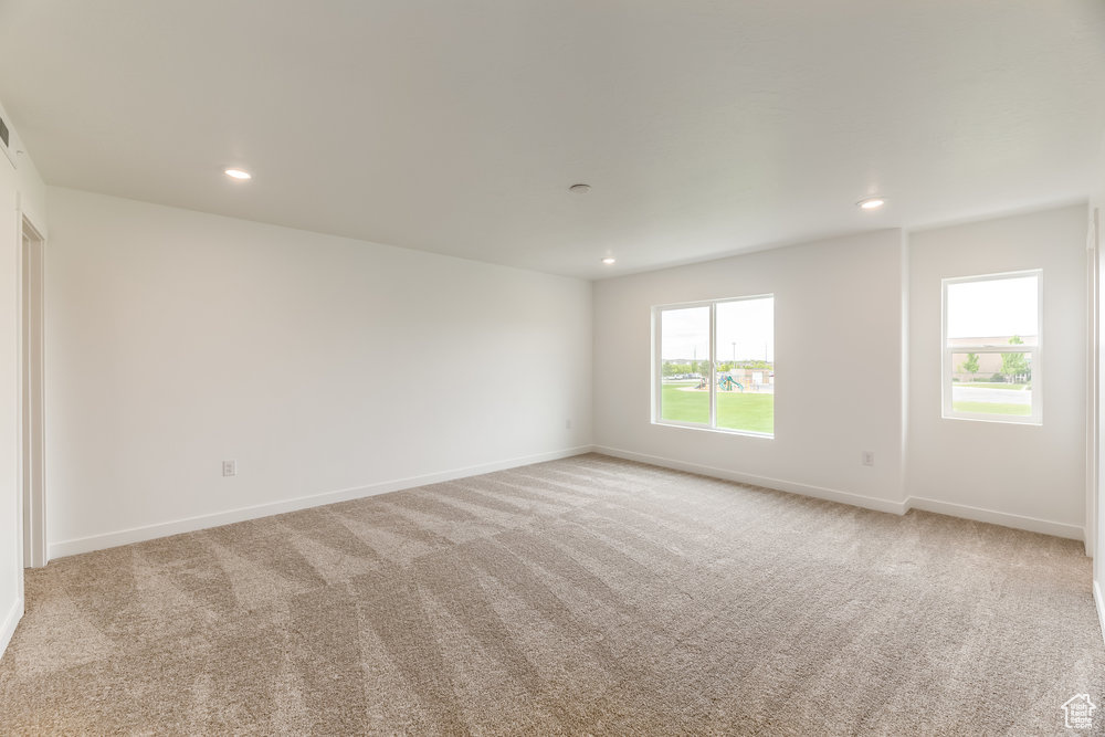 Empty room with light colored carpet, recessed lighting, and baseboards