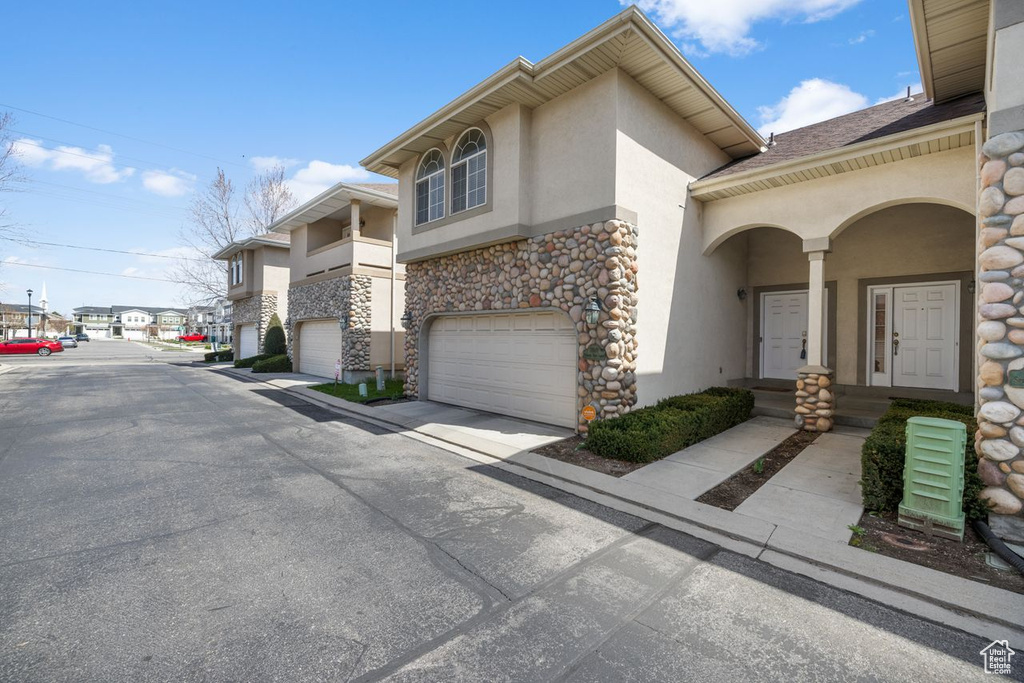 Exterior space featuring a garage, stucco siding, and stone siding