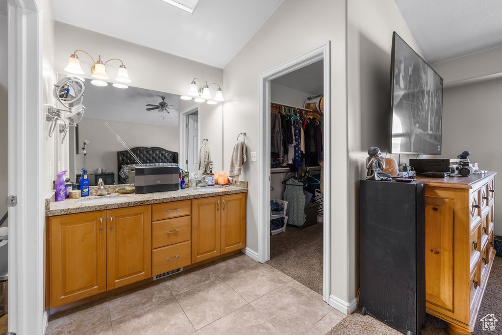 Bathroom featuring a sink, ceiling fan, a walk in closet, double vanity, and tile patterned flooring