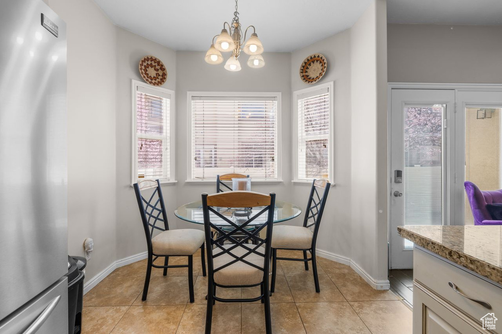 Dining room featuring light tile patterned floors, a notable chandelier, baseboards, and a wealth of natural light
