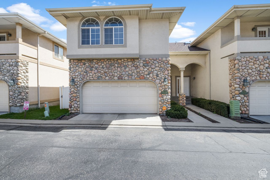View of front of house featuring driveway, stucco siding, and a garage