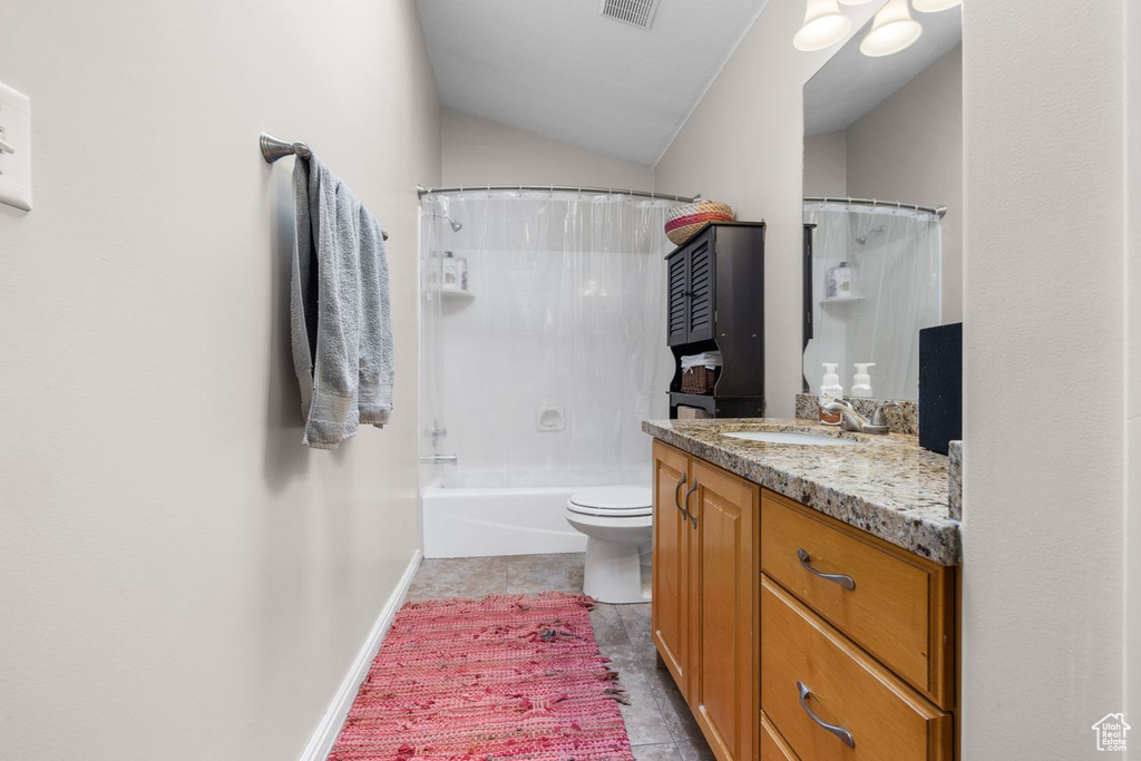 Bathroom with vanity, toilet, lofted ceiling, tile patterned floors, and baseboards