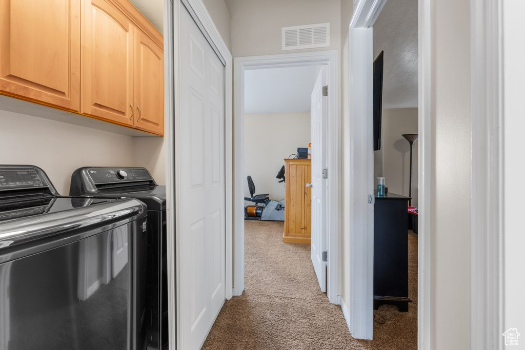Laundry area featuring carpet flooring, visible vents, separate washer and dryer, and cabinet space