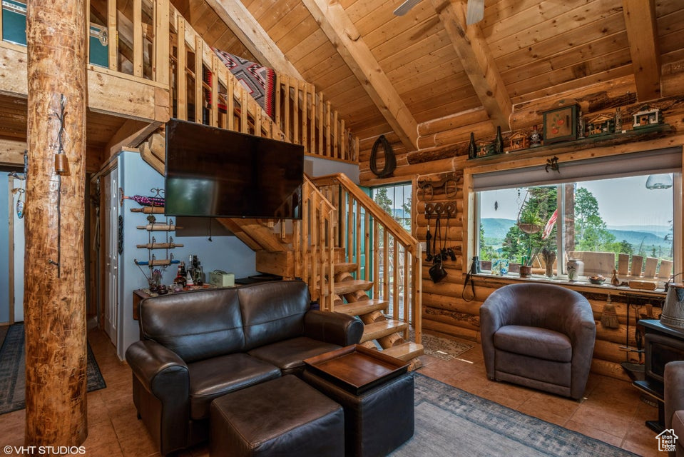 Living room featuring wood ceiling, rustic walls, tile patterned floors, and stairs