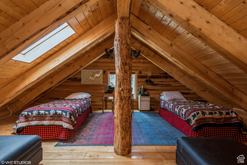 Bedroom with a skylight, wooden ceiling, wood-type flooring, and rustic walls