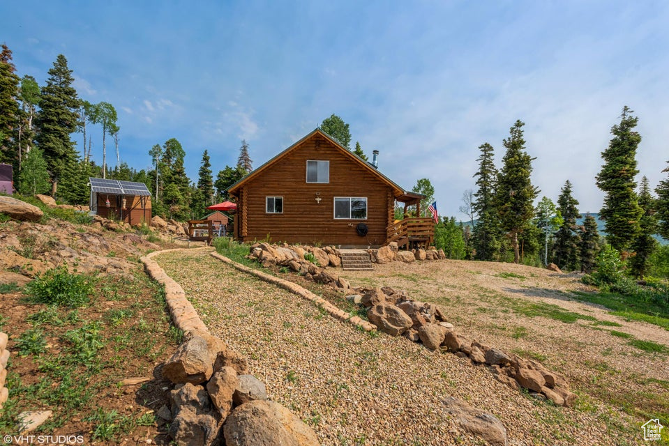 View of property exterior featuring log exterior, a greenhouse, and an outdoor structure