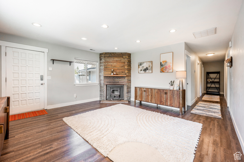 Living room featuring baseboards, dark wood-type flooring, recessed lighting, and a stone fireplace