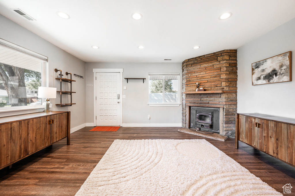 Living room with recessed lighting, dark wood-style floors, baseboards, and a wood stove
