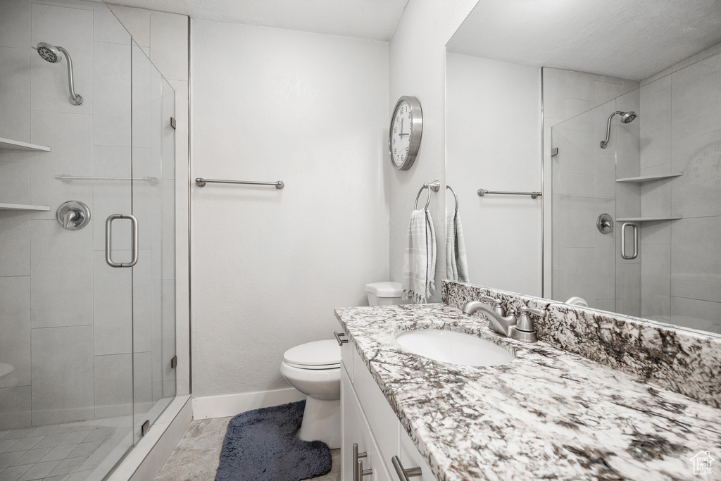 Bathroom with baseboards, toilet, vanity, and a shower stall