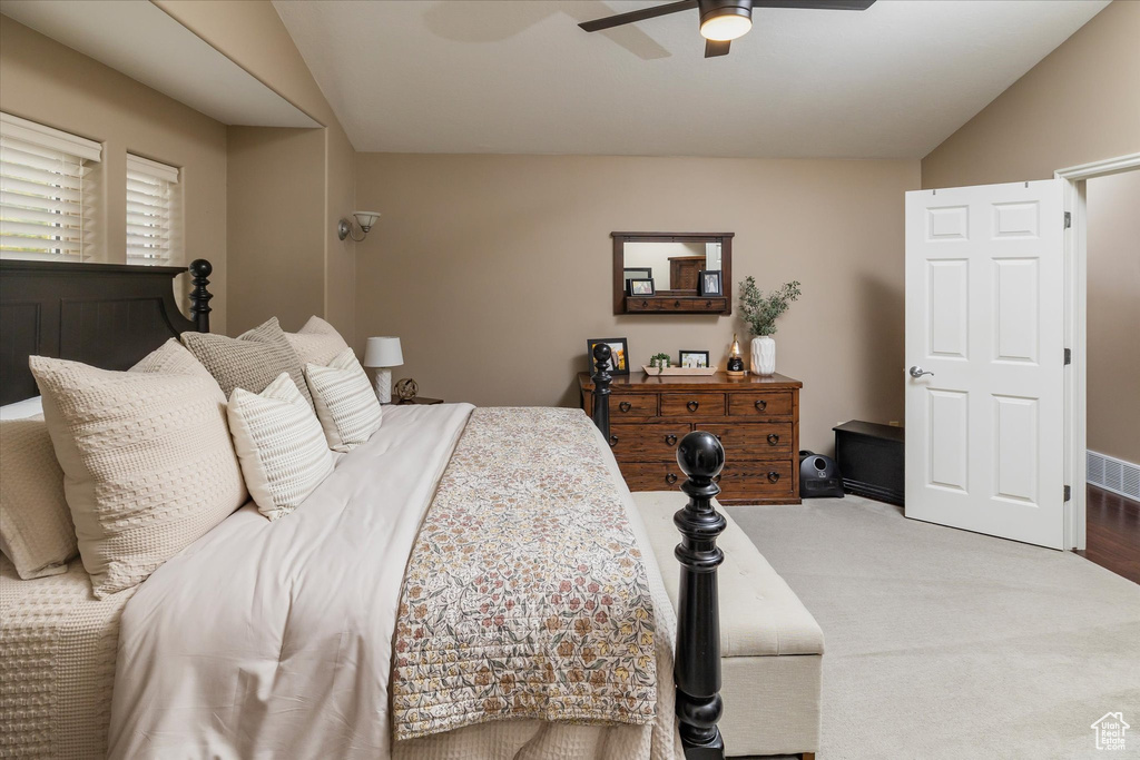 Bedroom with vaulted ceiling, a ceiling fan, and carpet floors