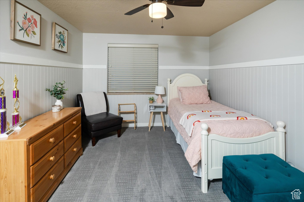 Carpeted bedroom featuring a wainscoted wall and a ceiling fan