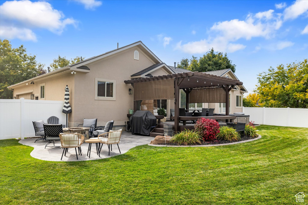 Rear view of house with a pergola, a patio area, stucco siding, and an outdoor living space with a fire pit