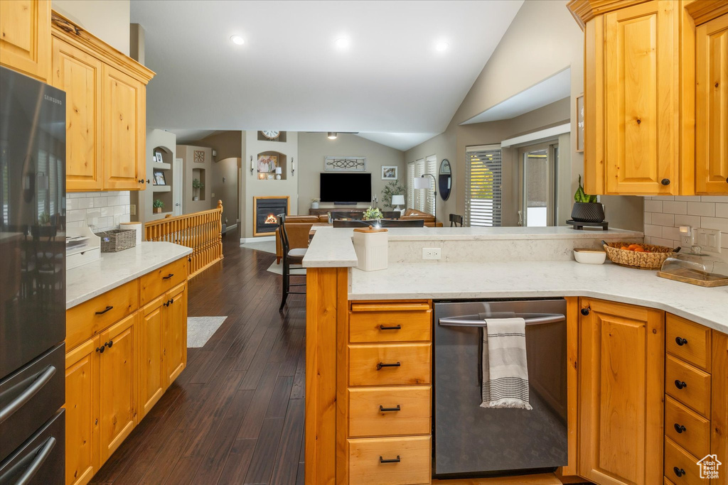 Kitchen featuring vaulted ceiling, open floor plan, freestanding refrigerator, a peninsula, and decorative backsplash