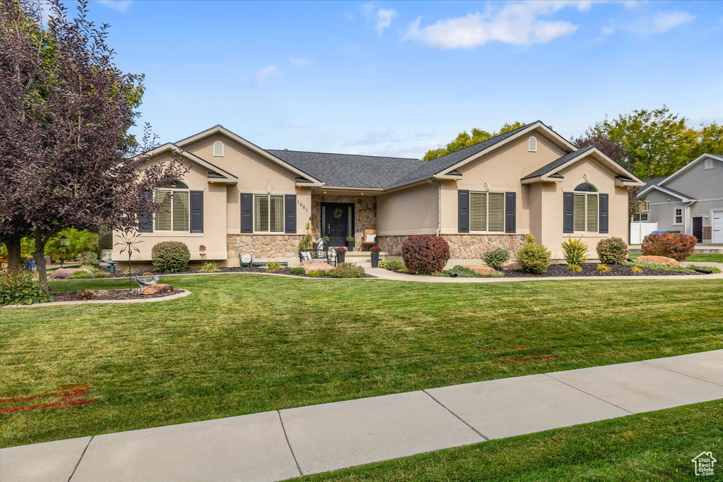 Ranch-style home featuring stucco siding, stone siding, and a front yard