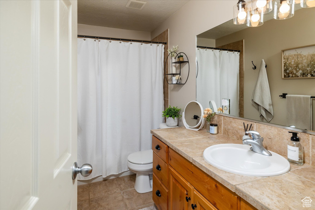 Full bath featuring vanity, toilet, a chandelier, tile patterned floors, and curtained shower