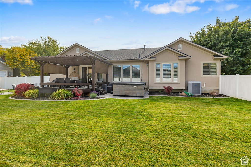 Rear view of house featuring a hot tub, a pergola, cooling unit, stucco siding, and an outdoor hangout area