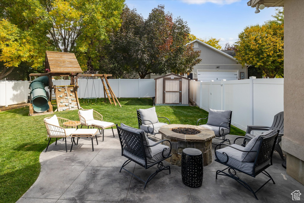View of patio with a playground and a fire pit