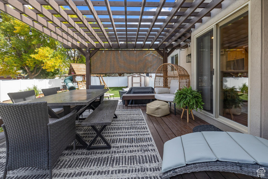 Deck with outdoor dining area, a fenced backyard, and a pergola
