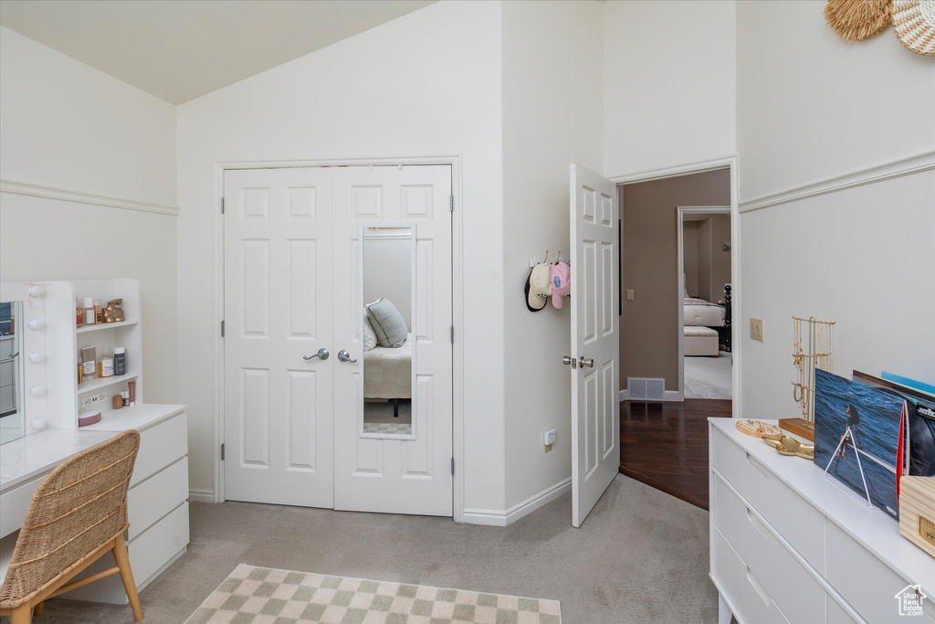 Bedroom featuring light carpet, a desk, high vaulted ceiling, a closet, and baseboards