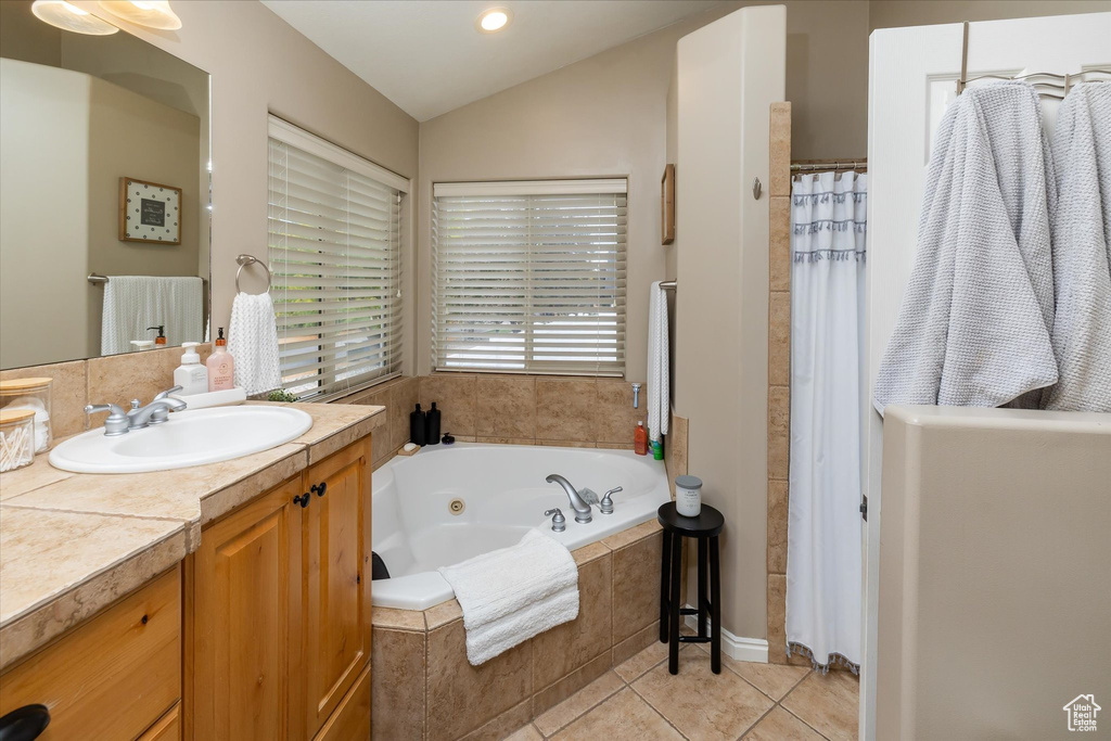 Bathroom with vanity, a jetted tub, vaulted ceiling, tile patterned flooring, and a shower with curtain