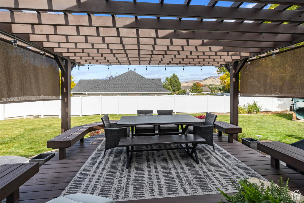 Wooden deck with outdoor dining area, a pergola, and a mountain view