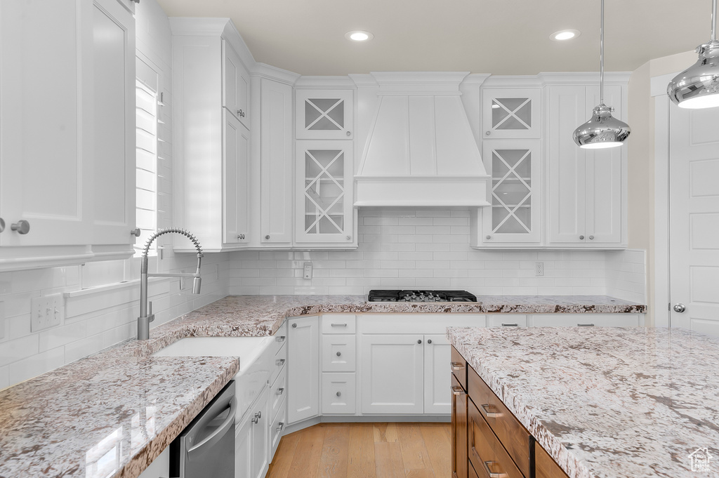 Kitchen with wall chimney range hood, stainless steel appliances, white cabinets, backsplash, and recessed lighting