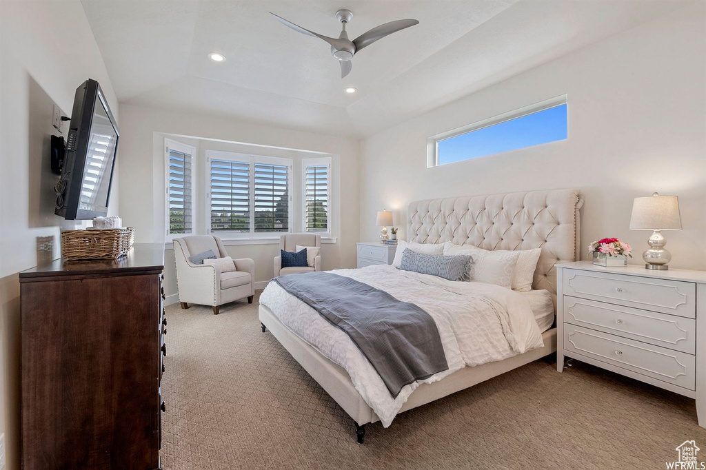 Bedroom with a raised ceiling, light carpet, recessed lighting, and a ceiling fan