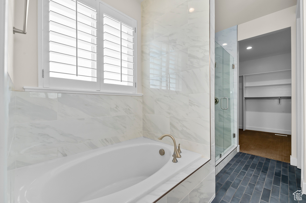 Bathroom featuring a bath, a stall shower, a spacious closet, and recessed lighting