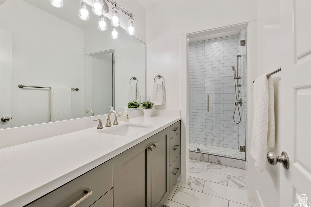 Bathroom featuring vanity, a stall shower, and marble look tile flooring