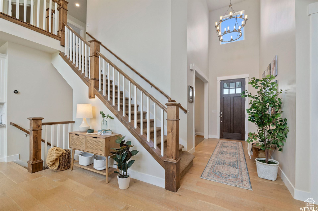 Entryway featuring wood finished floors, baseboards, a towering ceiling, a chandelier, and stairs