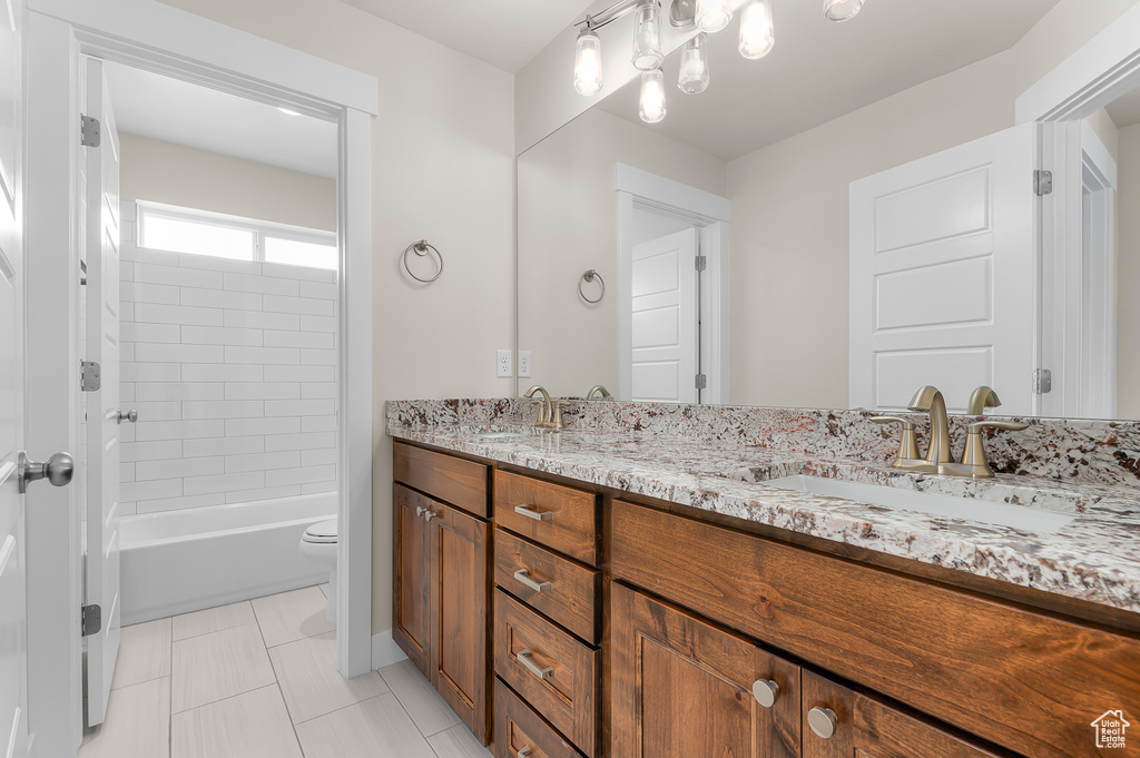 Full bathroom with double vanity, toilet, tile patterned floors, and shower / washtub combination