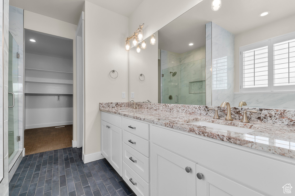 Full bath with a shower stall, double vanity, baseboards, a walk in closet, and recessed lighting