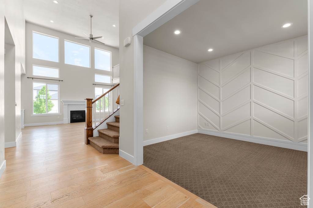 Spare room with ceiling fan, stairs, a glass covered fireplace, recessed lighting, and light wood-type flooring