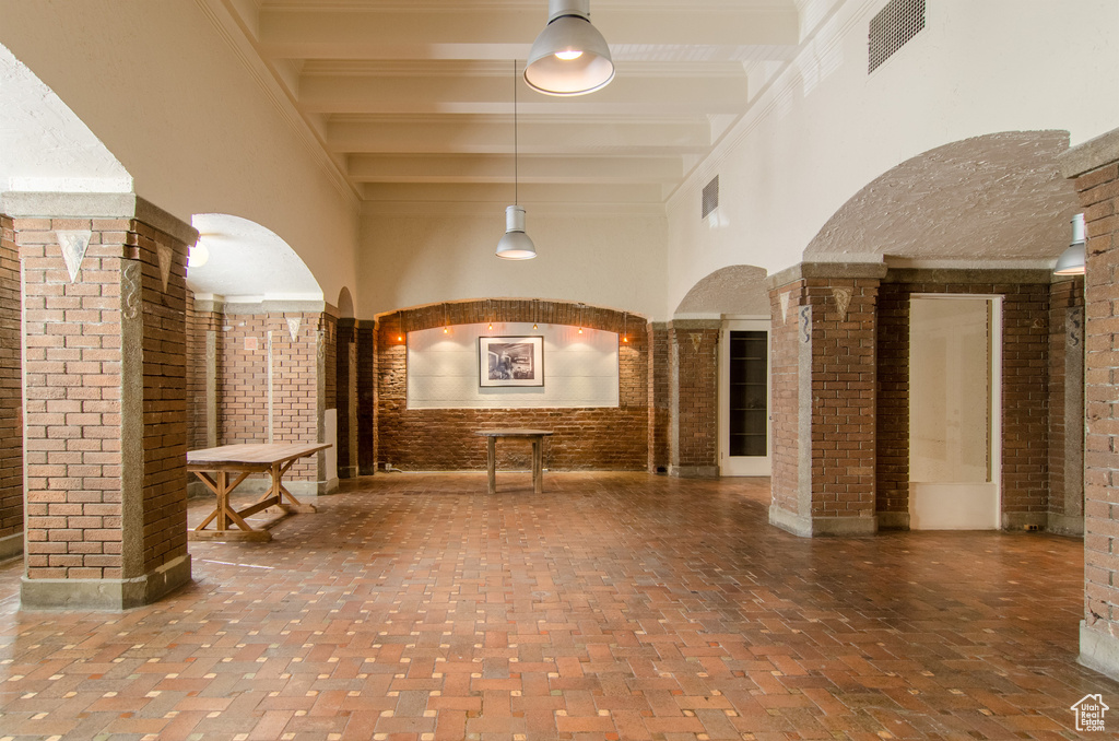 Community lobby with a high ceiling, beam ceiling, and brick wall