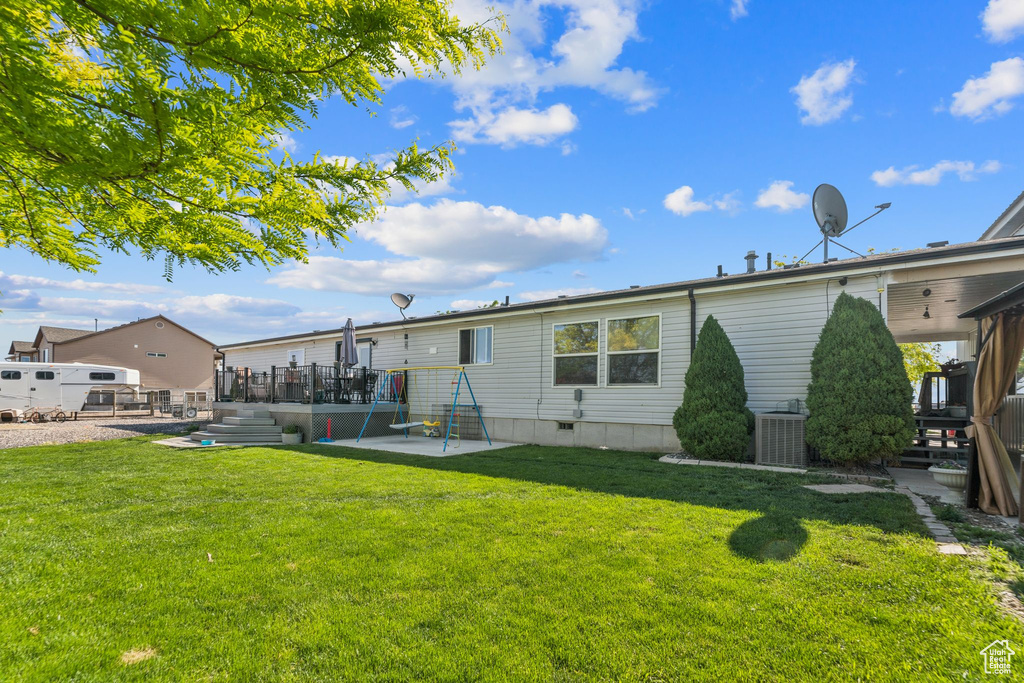 Rear view of house with a patio, a yard, a wooden deck, and central air condition unit
