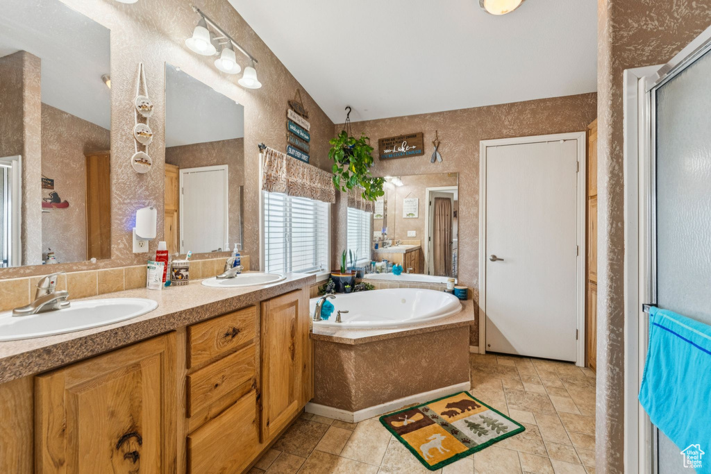 Full bath with a garden tub, double vanity, a shower stall, and stone finish flooring