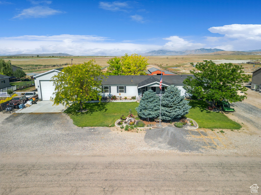 View of front of home featuring driveway, a mountain view, and a front yard