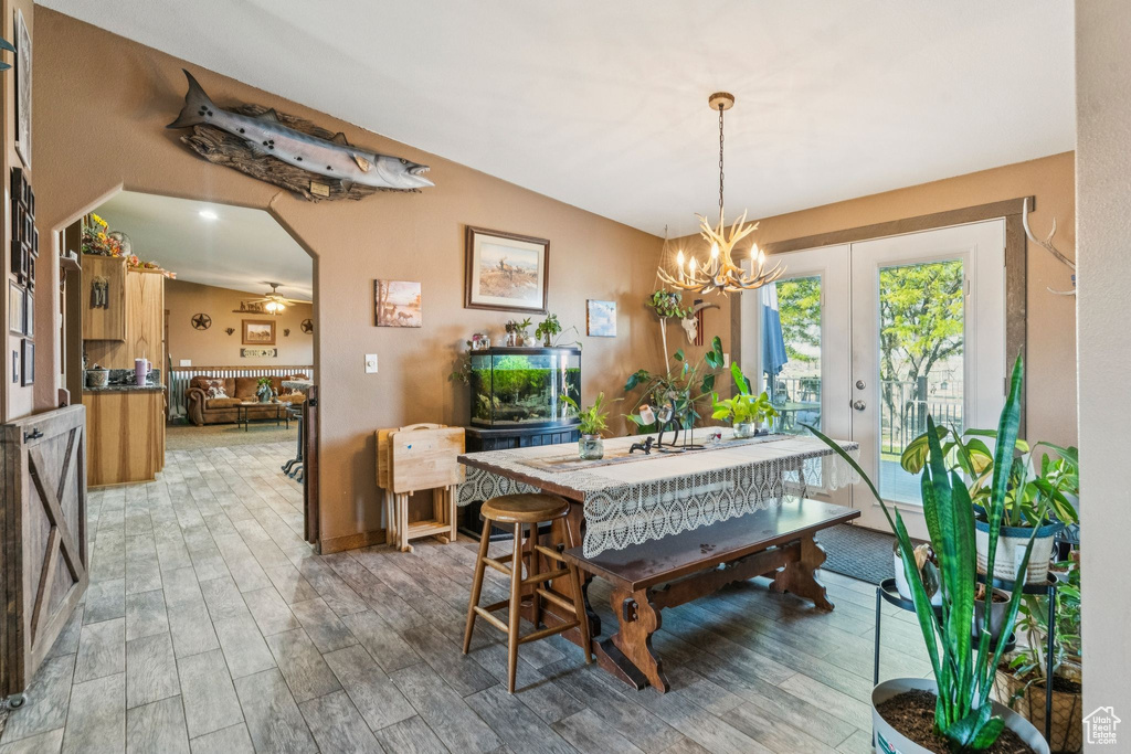 Dining space featuring light wood-type flooring, a chandelier, french doors, and baseboards