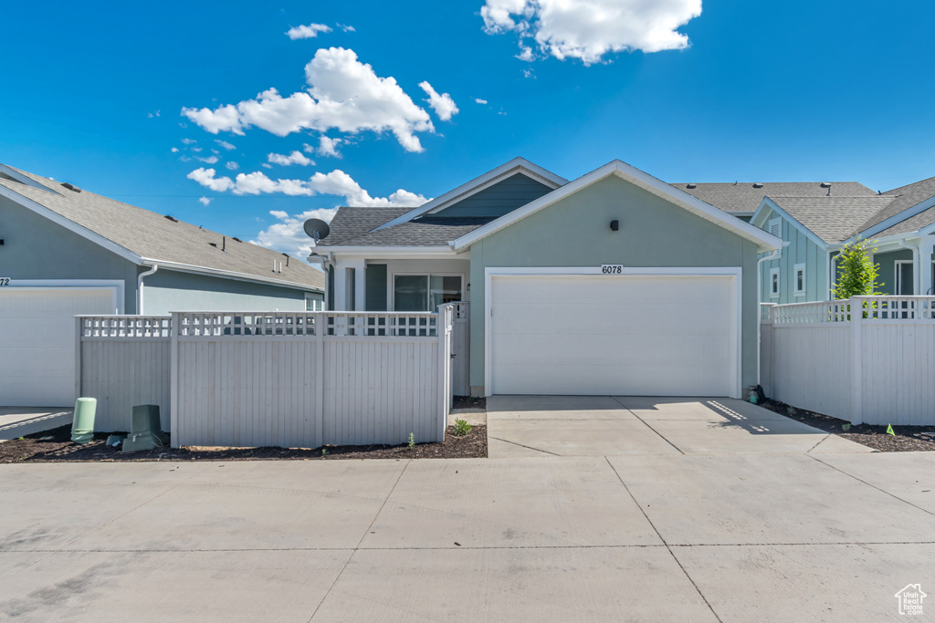 Ranch-style house with an attached garage, driveway, stucco siding, and roof with shingles