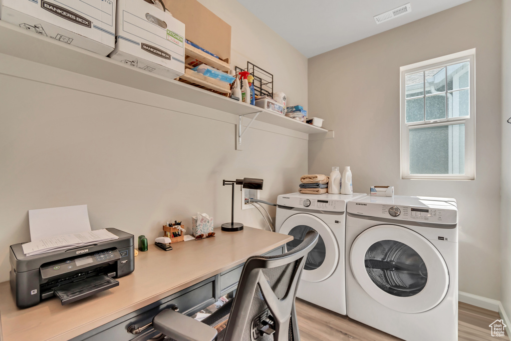 Laundry room with independent washer and dryer, light wood-style flooring, and a desk