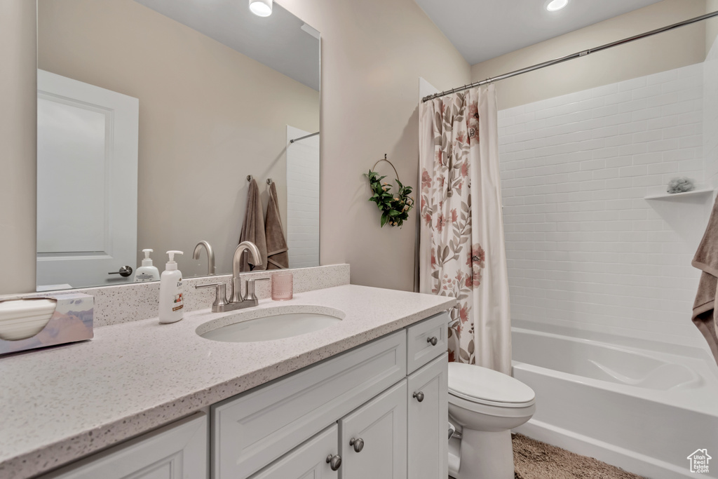 Full bathroom with vanity, shower / bathtub combination with curtain, and toilet