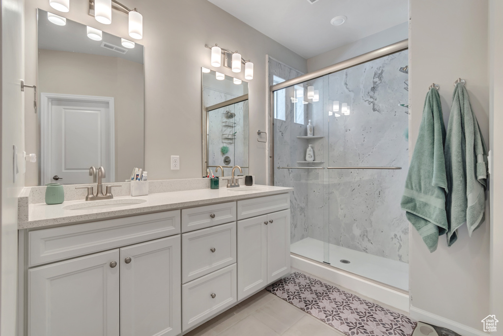Bathroom featuring a marble finish shower, double vanity, and tile patterned flooring