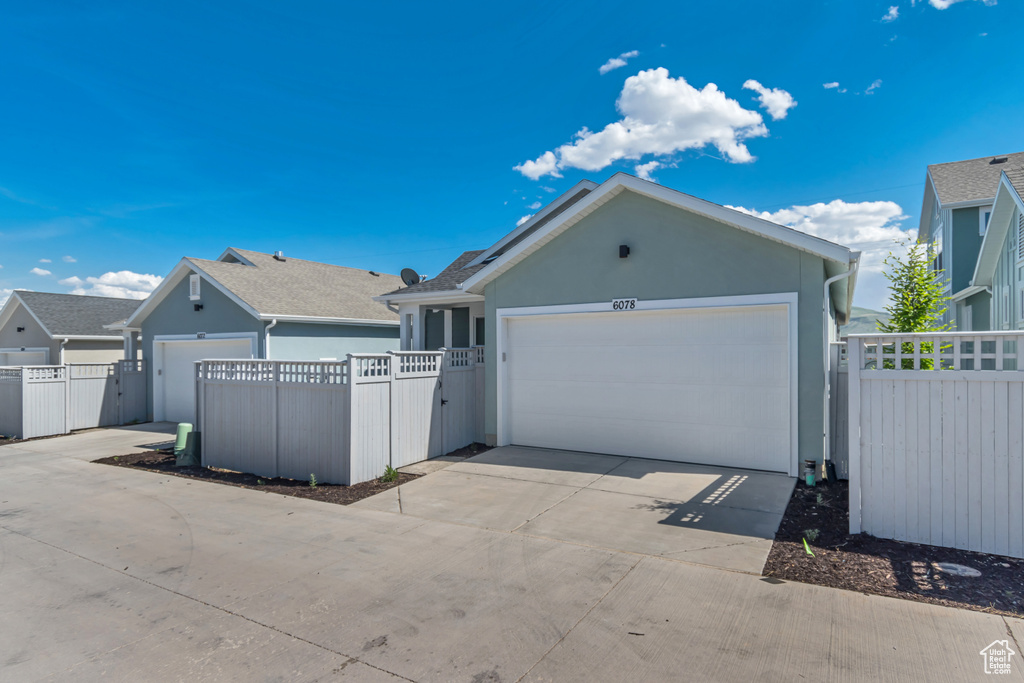View of front of property with stucco siding, concrete driveway, a garage, and a gate