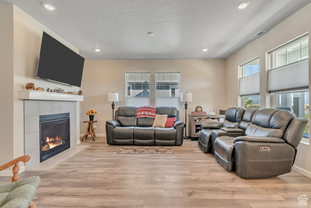 Living room featuring a tile fireplace, light wood finished floors, recessed lighting, and baseboards