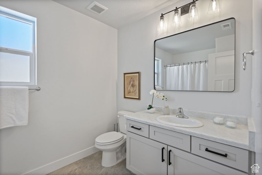 Bathroom with vanity, toilet, baseboards, and tile patterned flooring