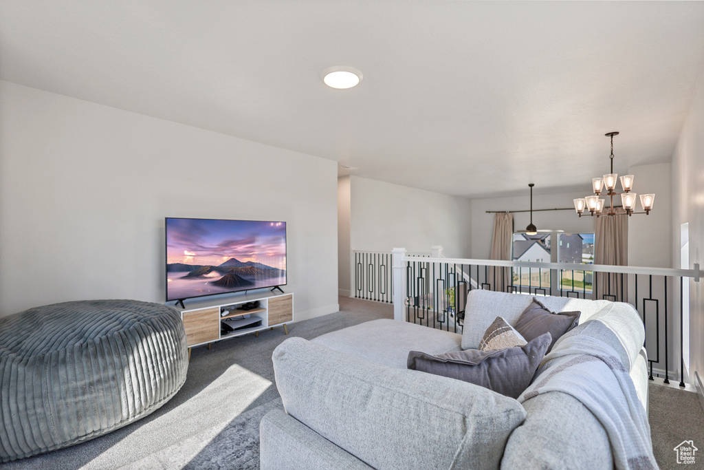 Living area featuring carpet, a chandelier, a ceiling fan, and baseboards